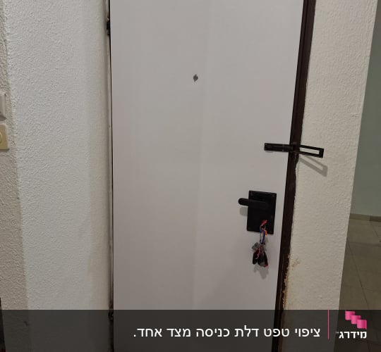 דלת לבנה עם ידית שחורה ומפתח תלוי